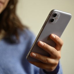 Hände benutzen ein Smartphone.