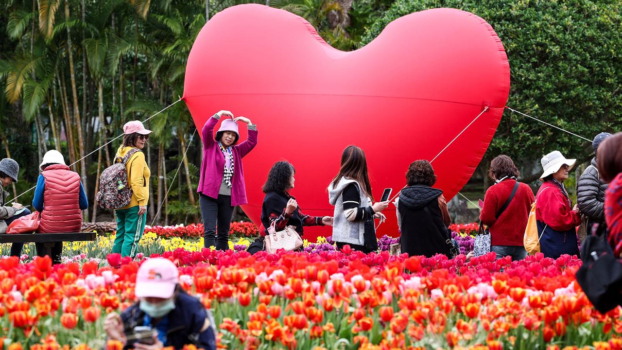 Vor einem großen Ballon in Herzform stehen Menschen, im Vordergrund ein Tulpenfeld.